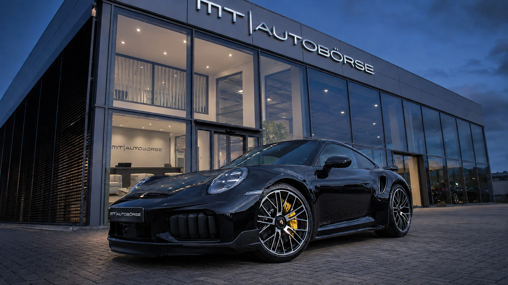 Porsche 911 vor der beleuchteten Glasfassade der MT Autobörse