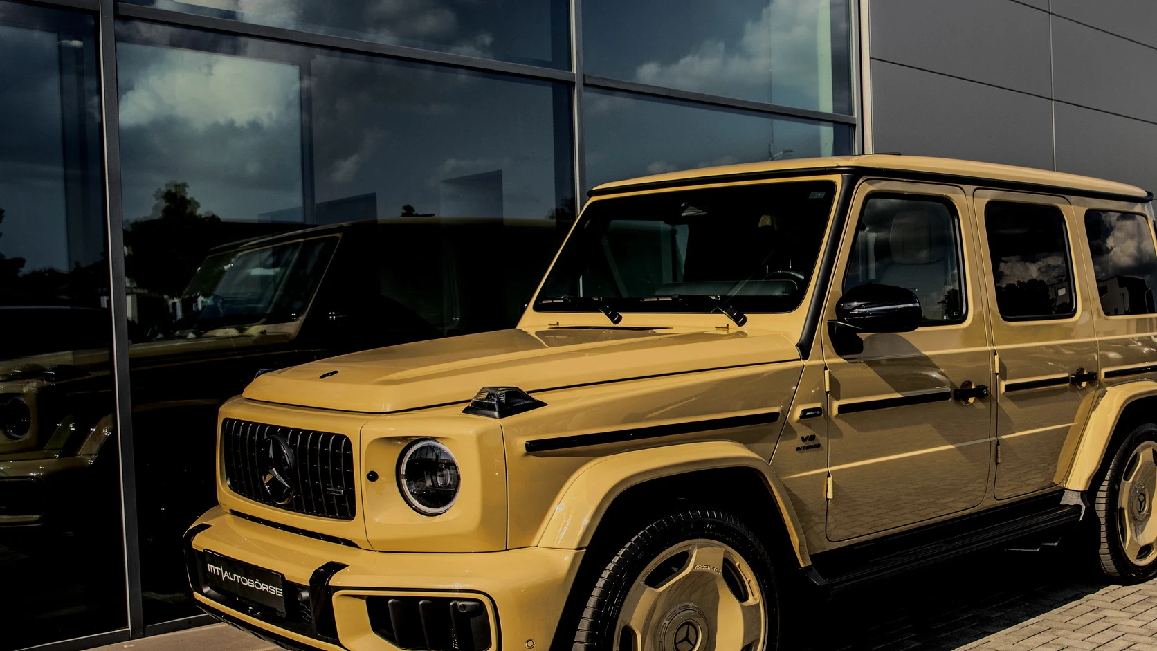 Gelbe Mercedes-Benz G-Klasse vor der Glasfassade der MT Autobörse